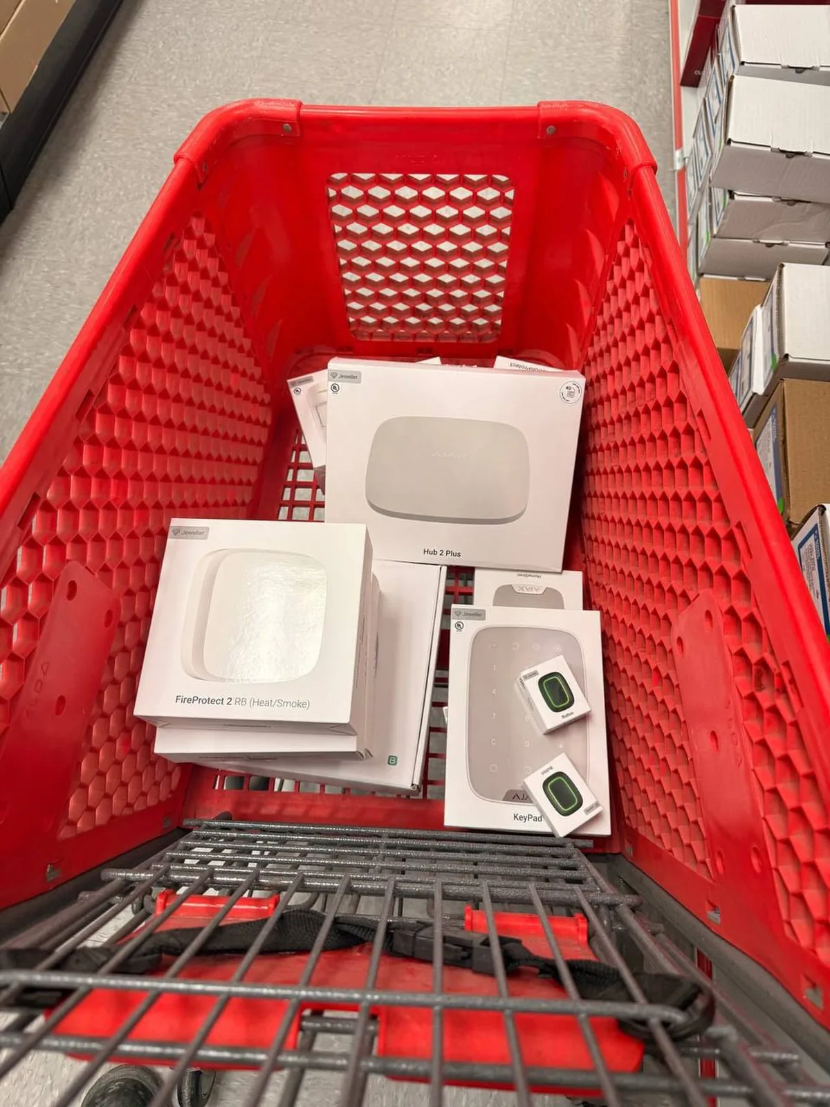 Ajax Systems hub, motion detectors and keypad boxes in a shopping cart before a Toronto install