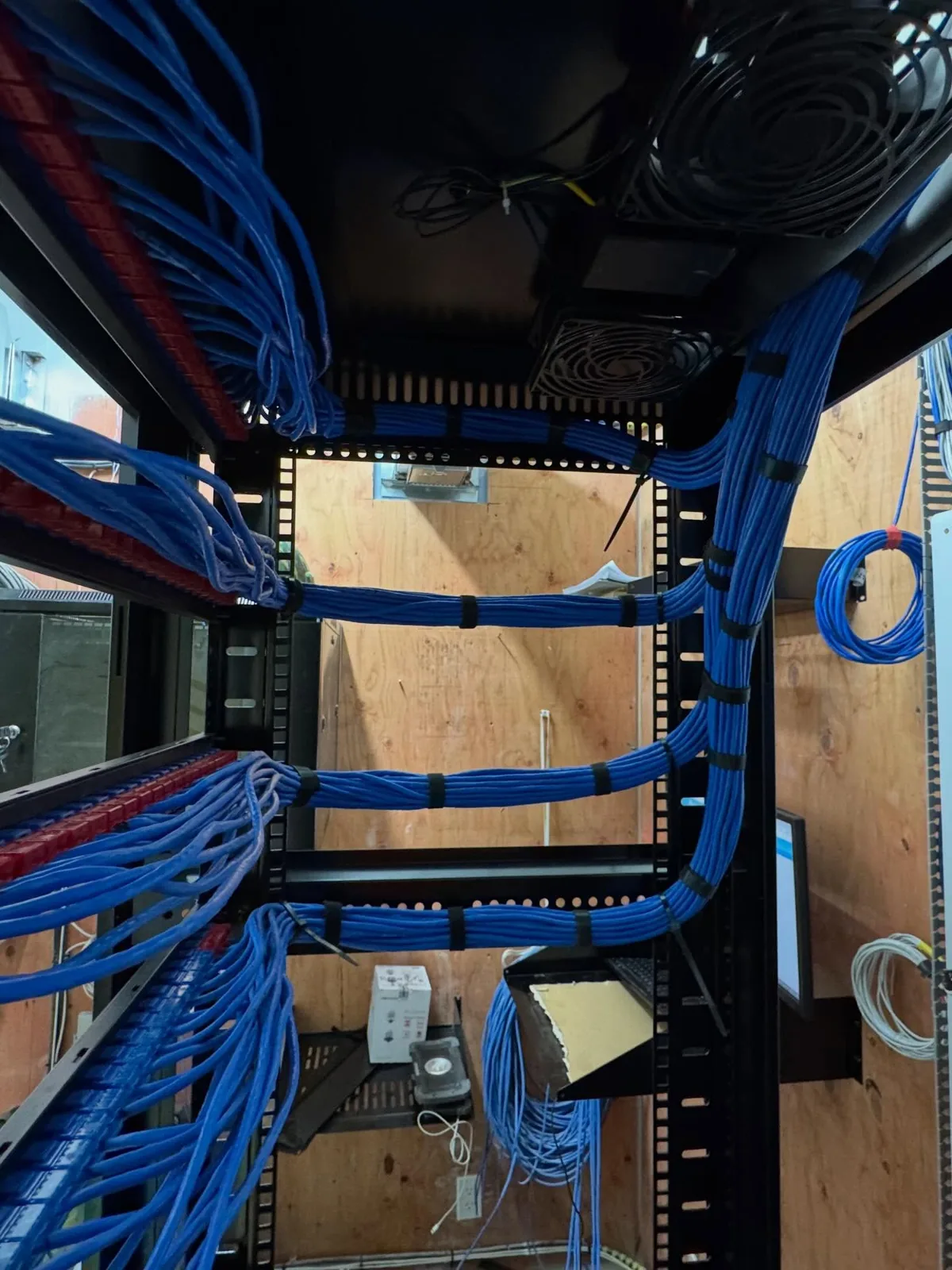 Rack and backboard with blue cables dressed to proper bend radius