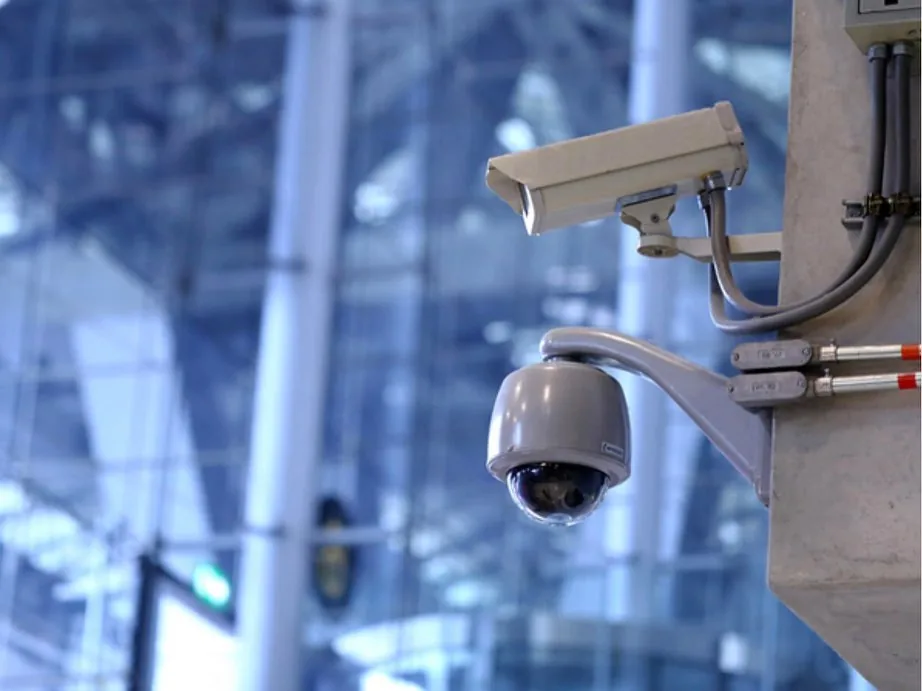 Bullet and dome cameras on a concrete column of a glass building