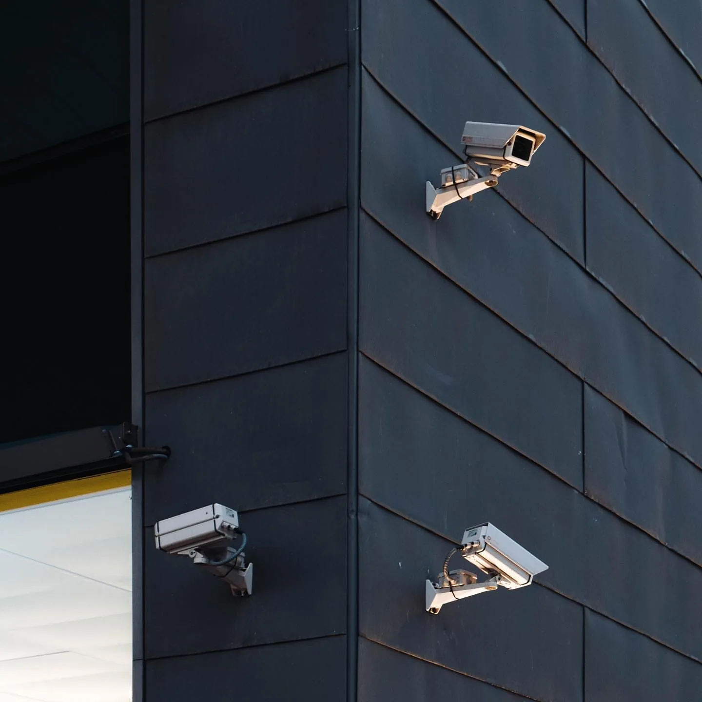 Three bullet cameras on the corner of black siding