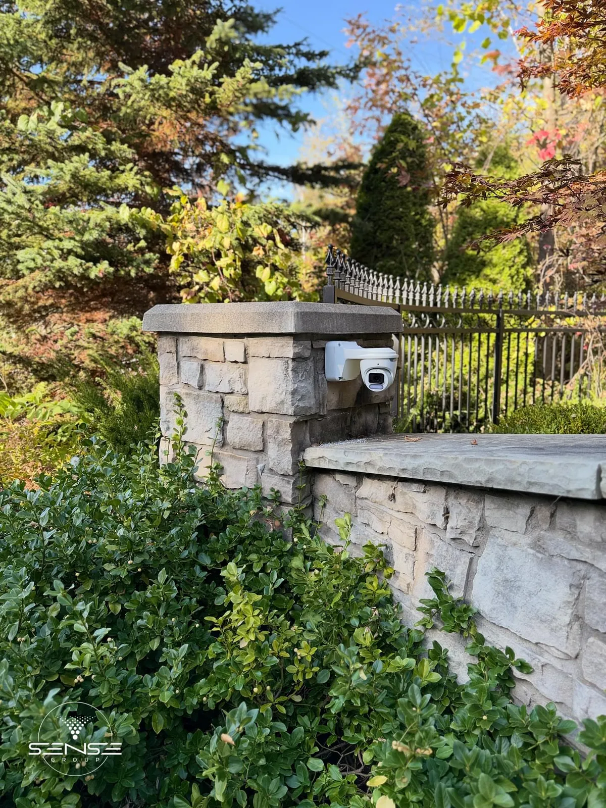 Owl View 8MP 4K camera on a stone gate pillar beside a driveway in autumn