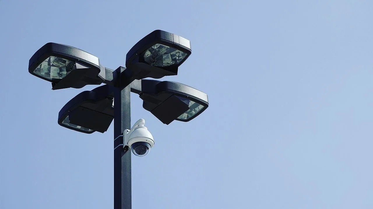 PTZ camera mounted on a light pole beneath floodlights