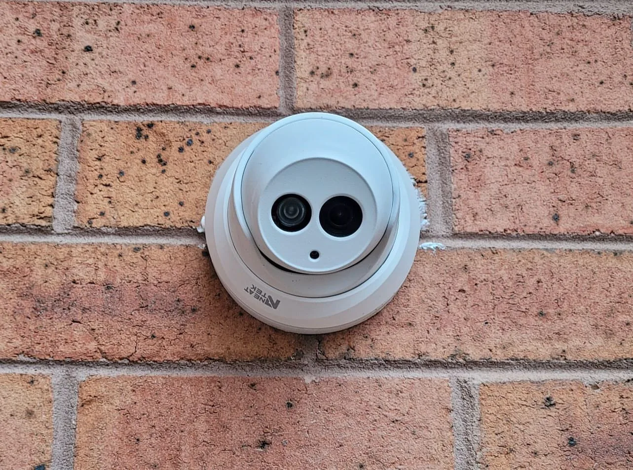 White turret camera on a red brick wall