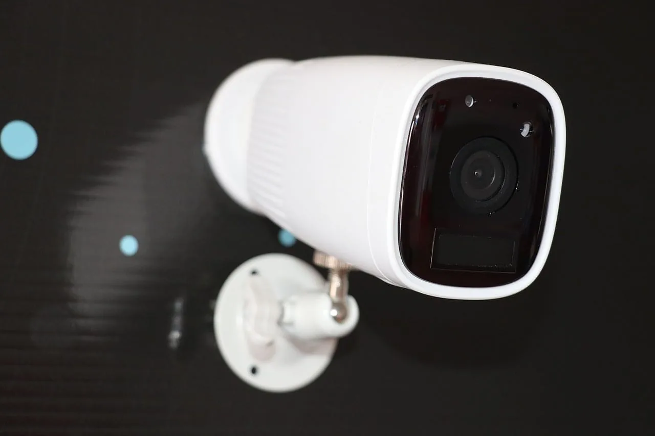 White bullet camera with wall mount on a black background