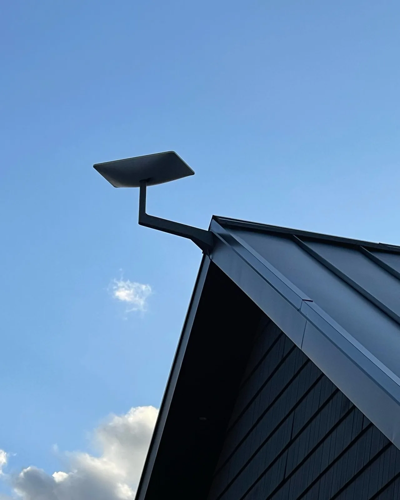 Starlink dish on the peak of a black metal roof in Creemore