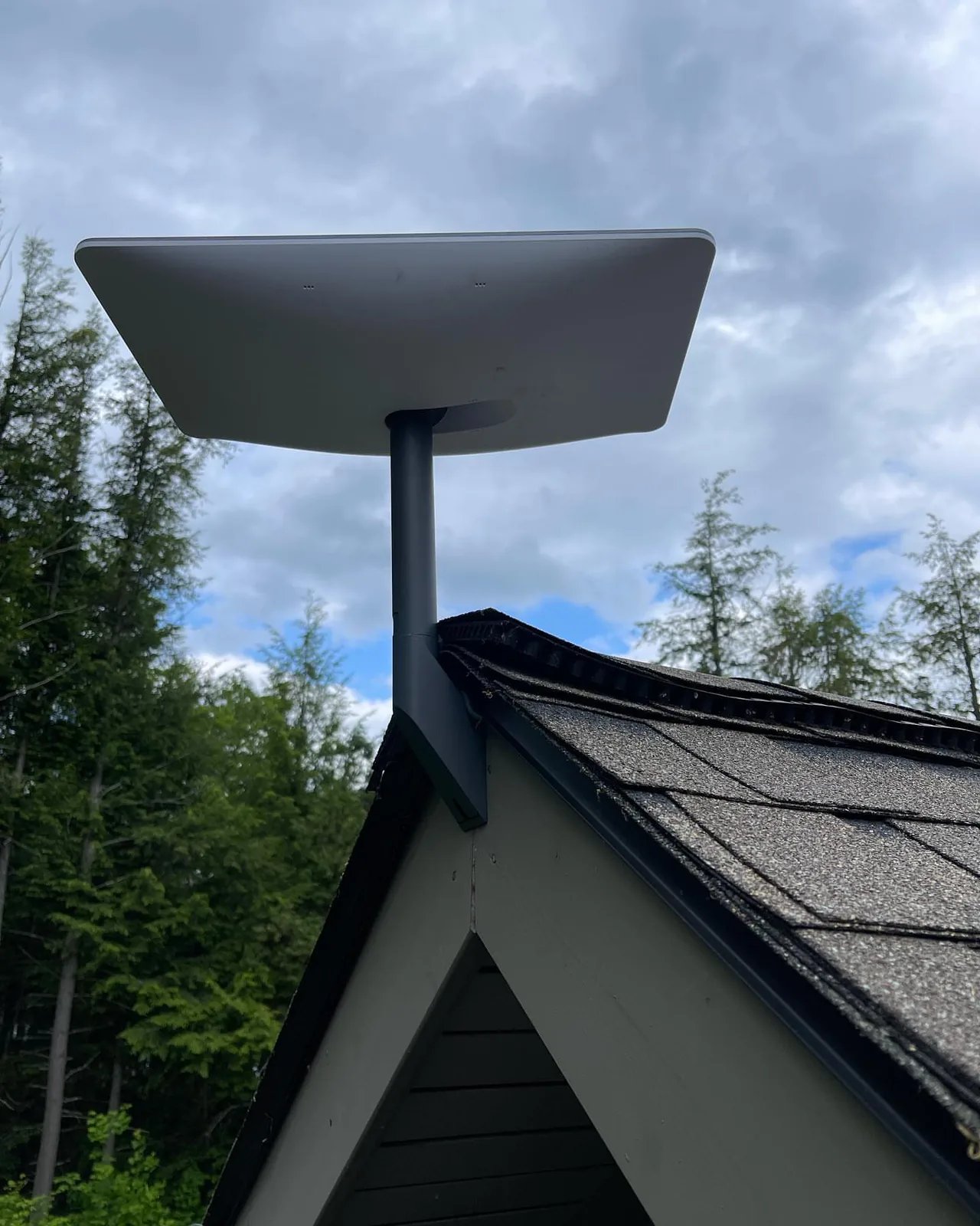 Starlink dish on a cottage gable under dramatic clouds