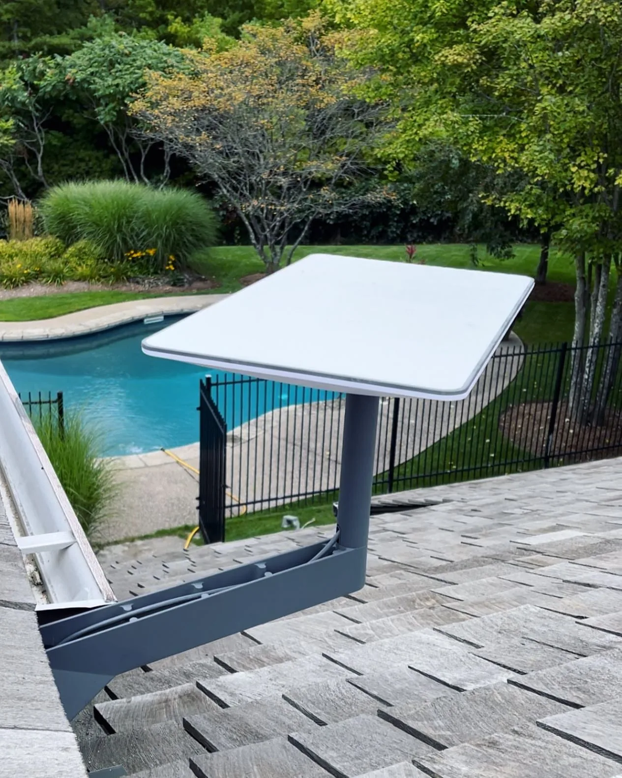 Starlink dish on a wall mount beside a backyard pool