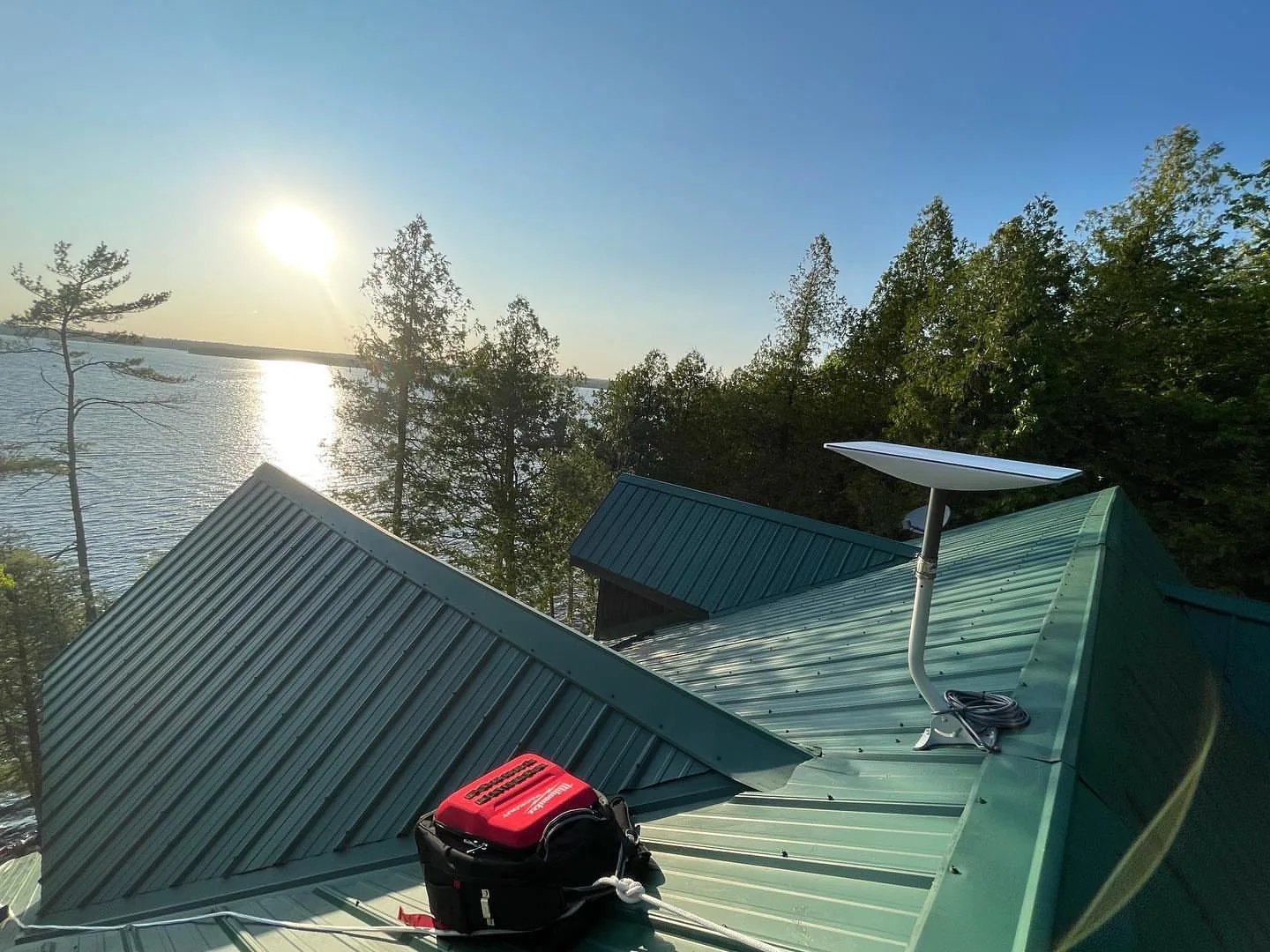 Starlink dish on a green metal roof beside a lake at sunset in Oro-Medonte