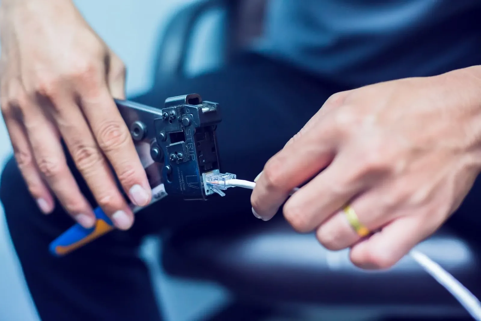 Technician using a crimping tool to fit an RJ45 connector to a network cable