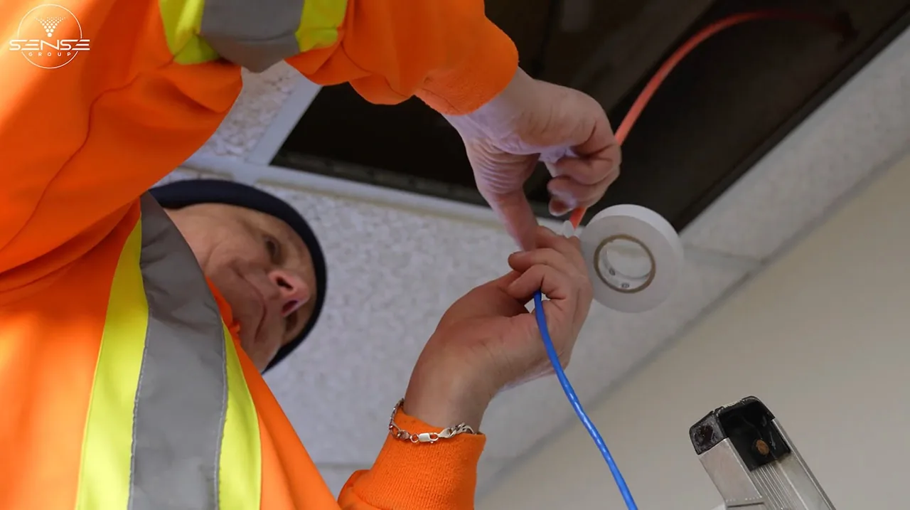 Technician terminating a cable on a ladder