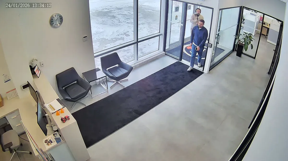 Camera footage of an office lobby entrance with two people entering