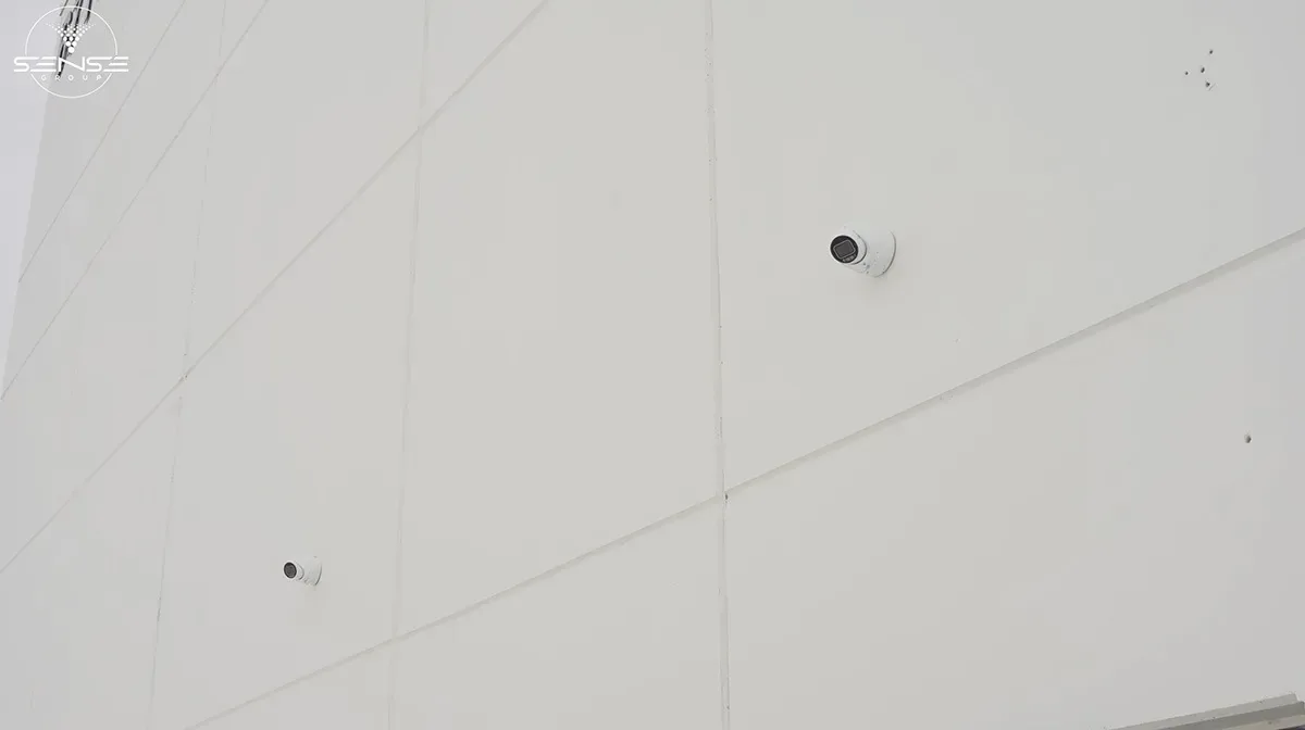 Two bullet cameras on a white exterior warehouse wall