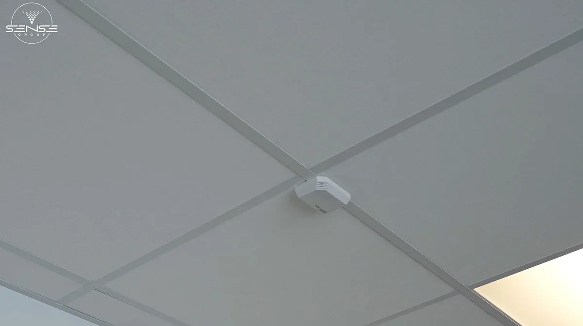 White UniFi access point on a drop ceiling