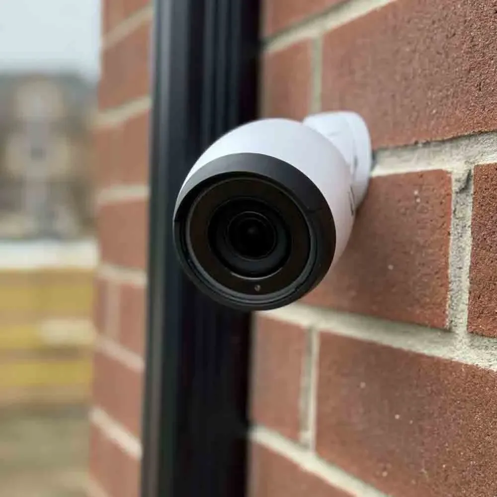 White bullet camera mounted on a red brick wall