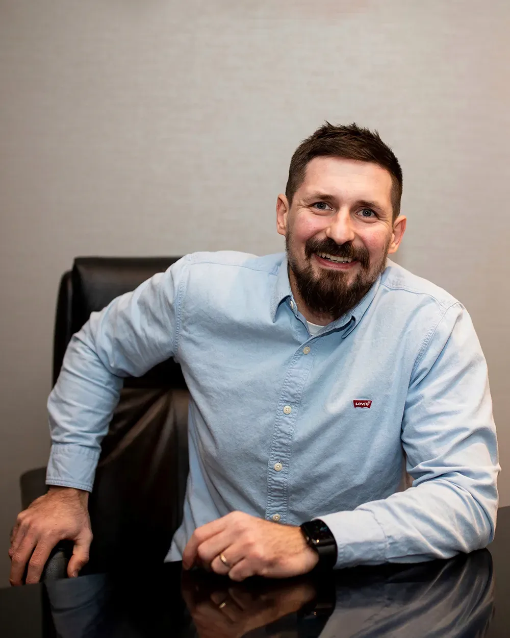 Vitaly Sukhina, founder of Sense Group, seated at a desk in a blue shirt and smiling