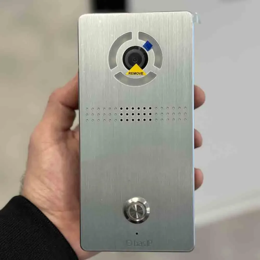 Technician holding a stainless BAS-IP video intercom panel with camera, speaker and call button